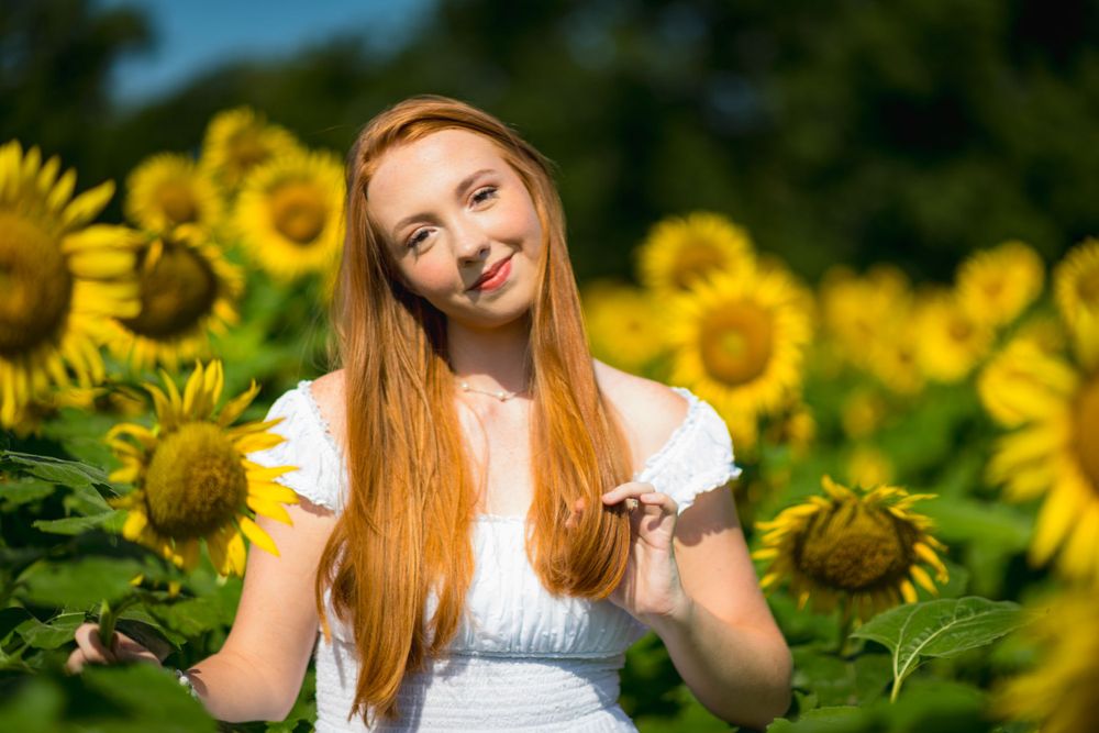 Cheerful pose among bright yellow sunflowers on a sunny summer day.