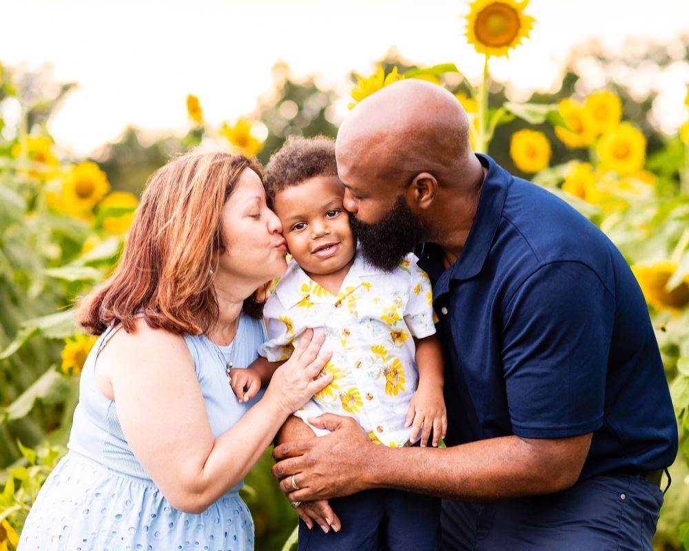 Family photoshoot in a vibrant sunflower field during golden hour showing tender moments and embraces.
