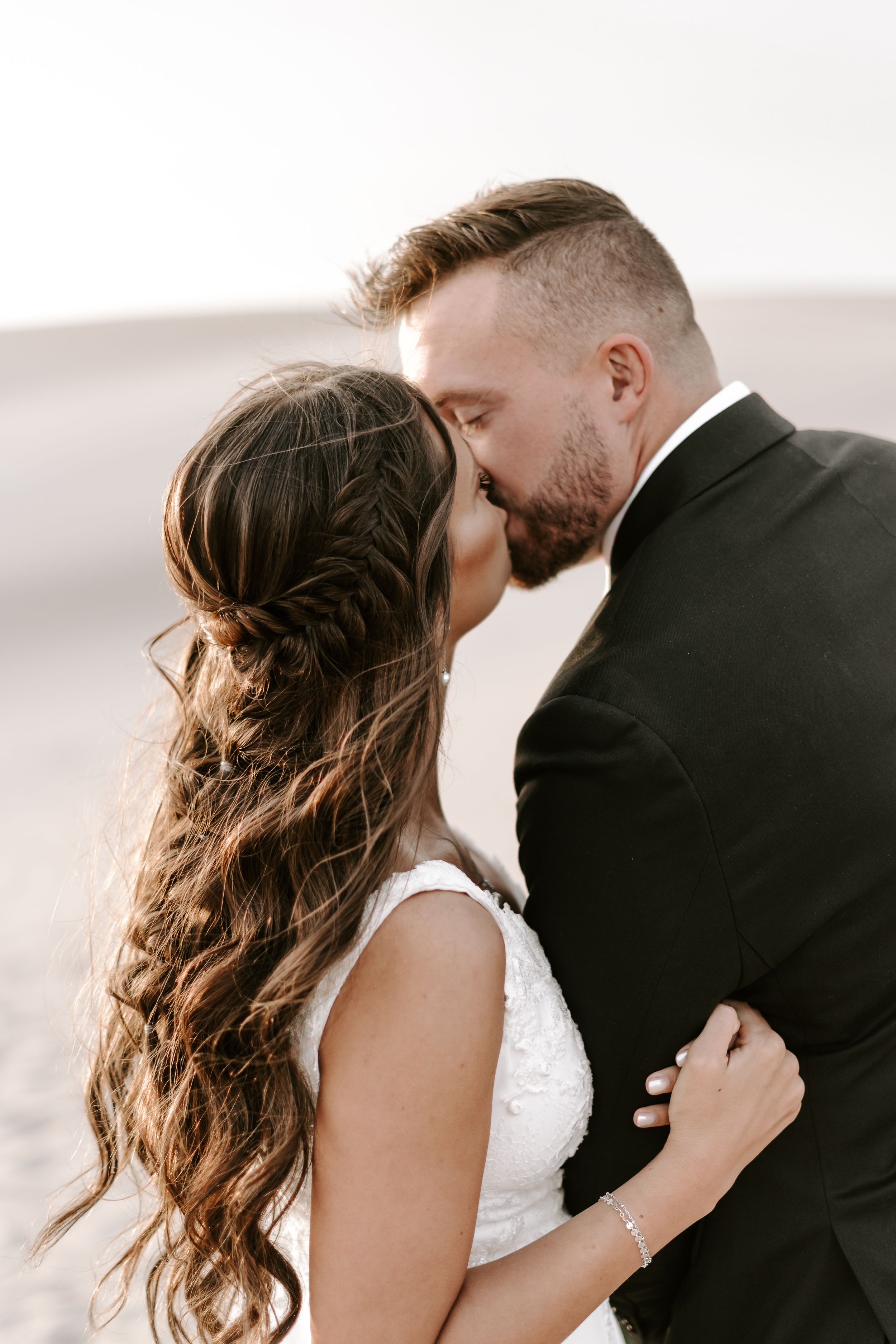 Intimate wedding portrait showing detailed braided hairstyle against desert background.