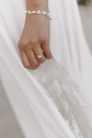 Close-up of delicate bridal jewelry with diamond ring and crystal bracelet.