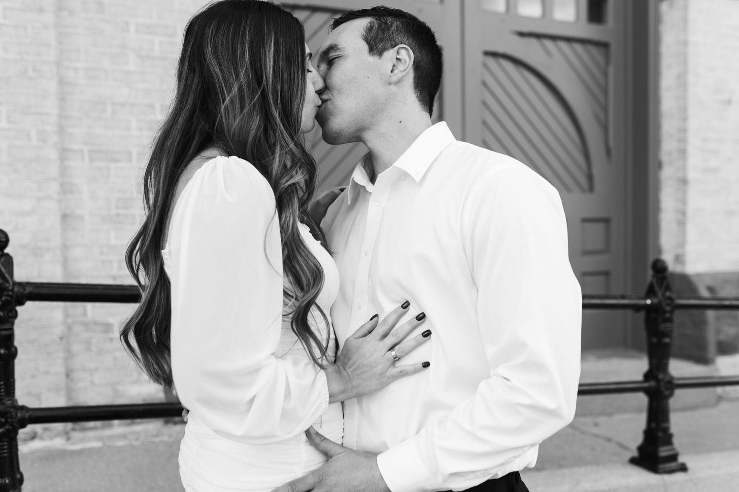 man and woman kiss outside in black and white image