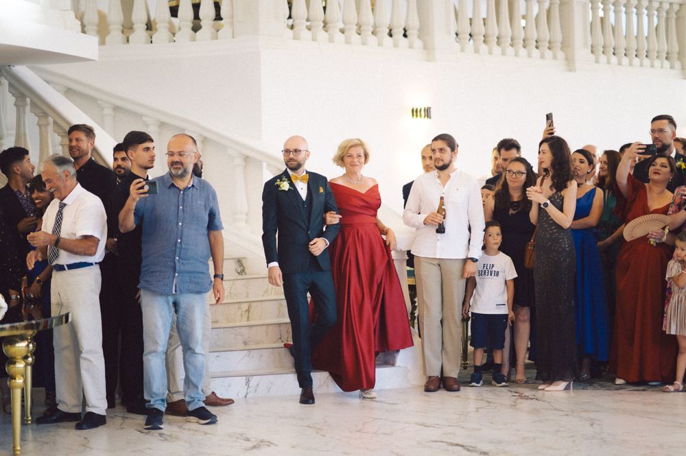 Wedding guests gathered on elegant white stairs watching a celebration unfold.