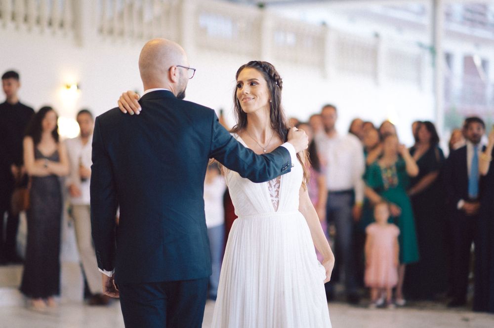 Couple sharing their first dance surrounded by guests in an elegant white ballroom.