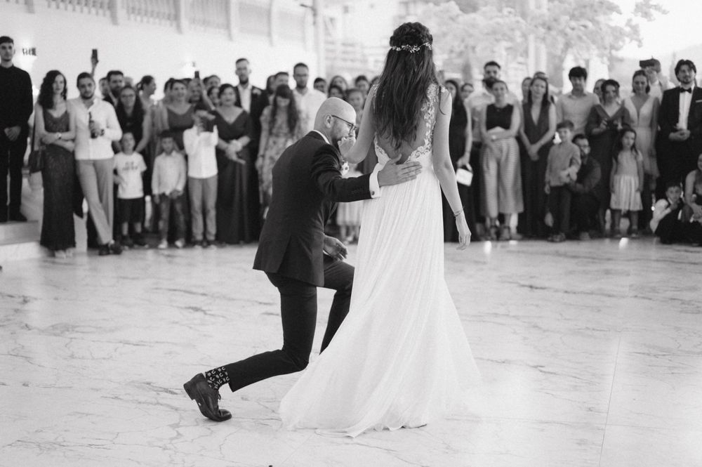Black and white photo of romantic dance move during wedding reception with guests watching.
