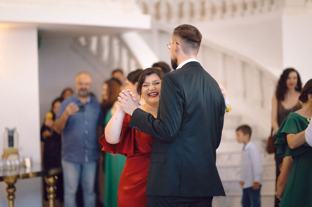 A couple dances together in an elegant venue as guests look on during a wedding celebration.