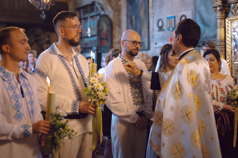 Eastern Orthodox clergy conducting a traditional religious ceremony with ornate white and gold vestments.