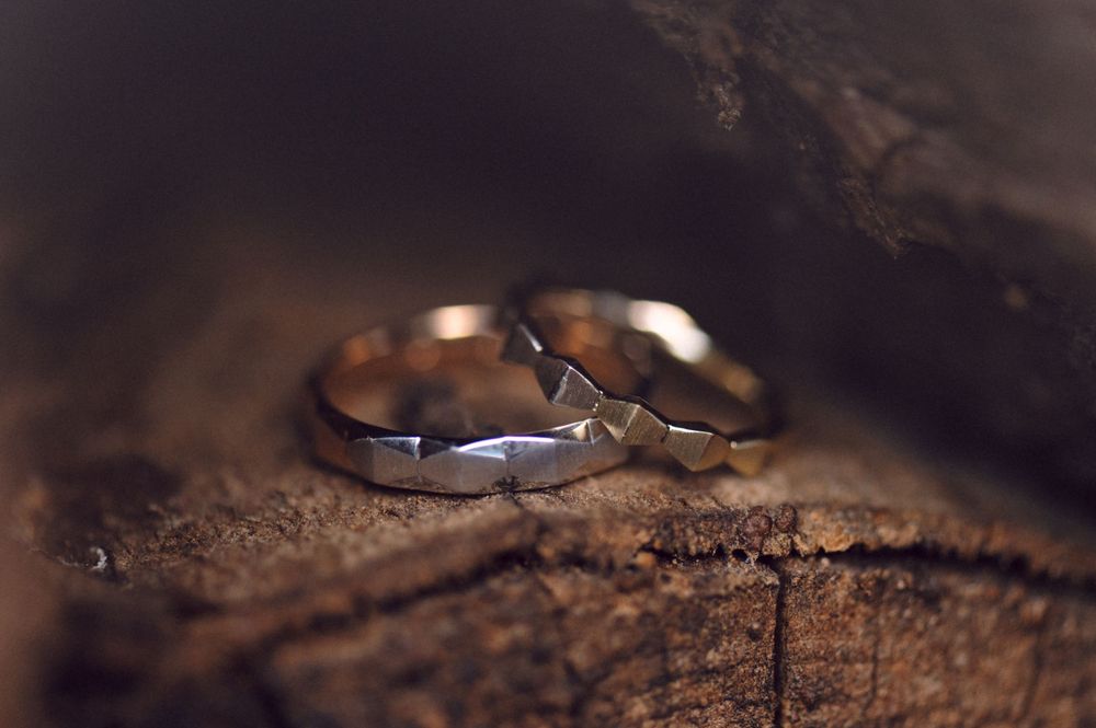 Two wedding bands photographed on a rustic wooden surface with dramatic lighting.