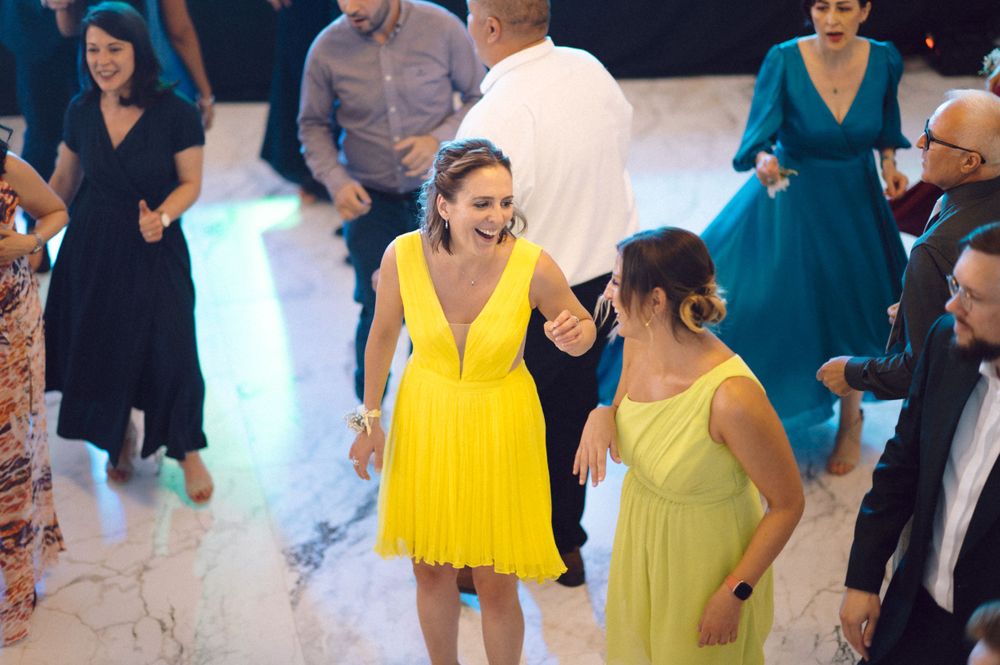 Party guests in colorful dresses enjoying themselves on a dance floor.