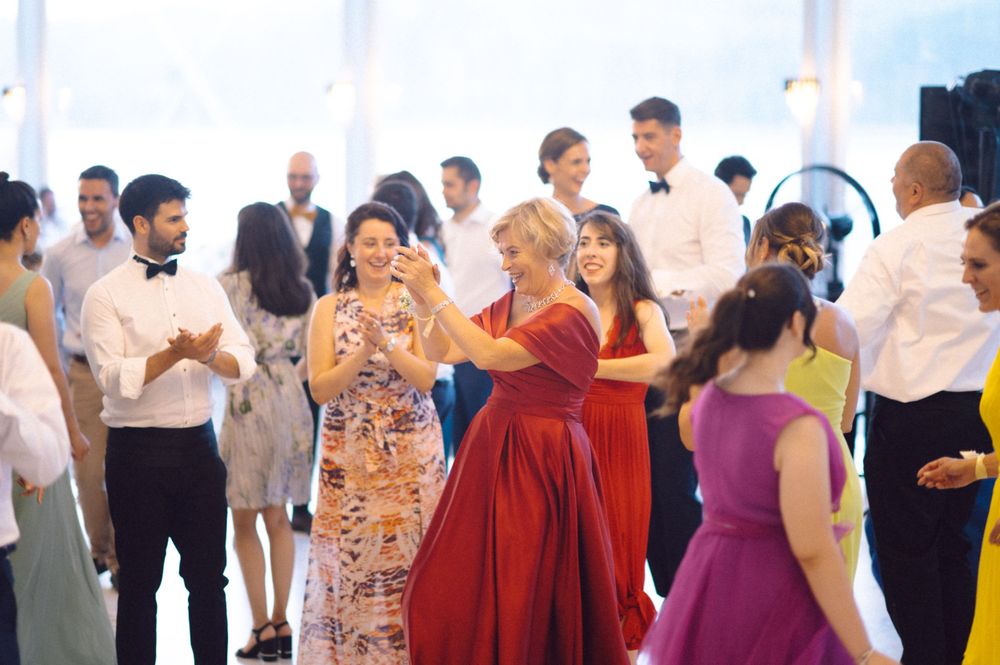 Wedding guests dancing and mingling at a reception in bright formal attire.