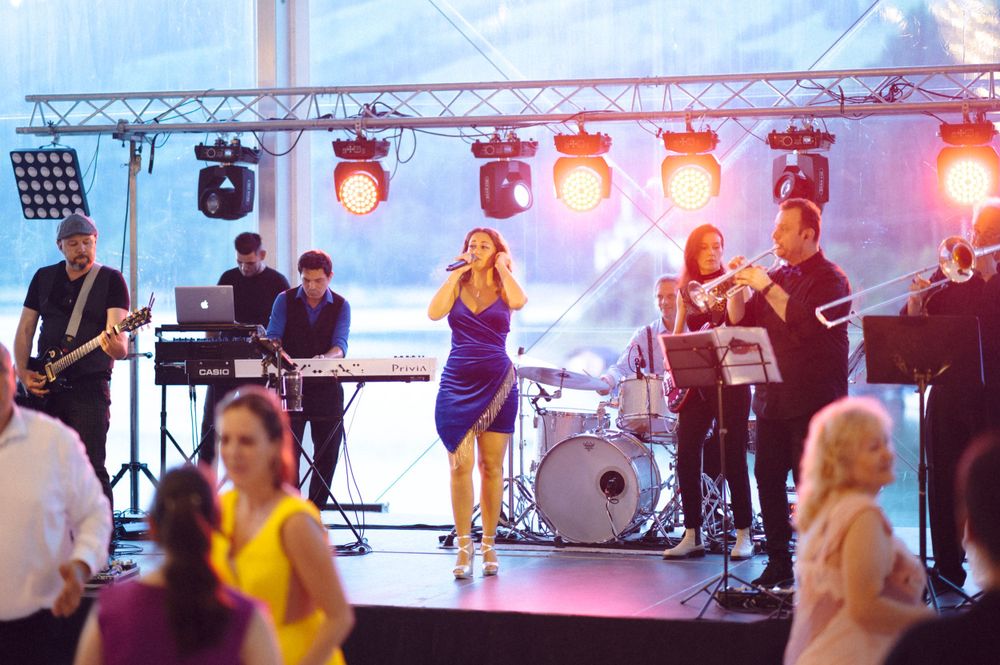 Live band performing on stage with colorful lighting at an evening event.
