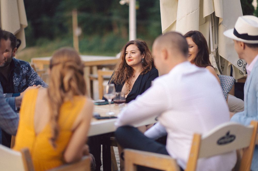 People enjoying an outdoor dining gathering on a patio with umbrellas during a summer afternoon.