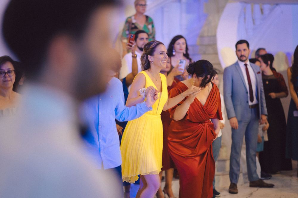 Guests dancing and celebrating at an elegant indoor party with colorful dresses and lighting.