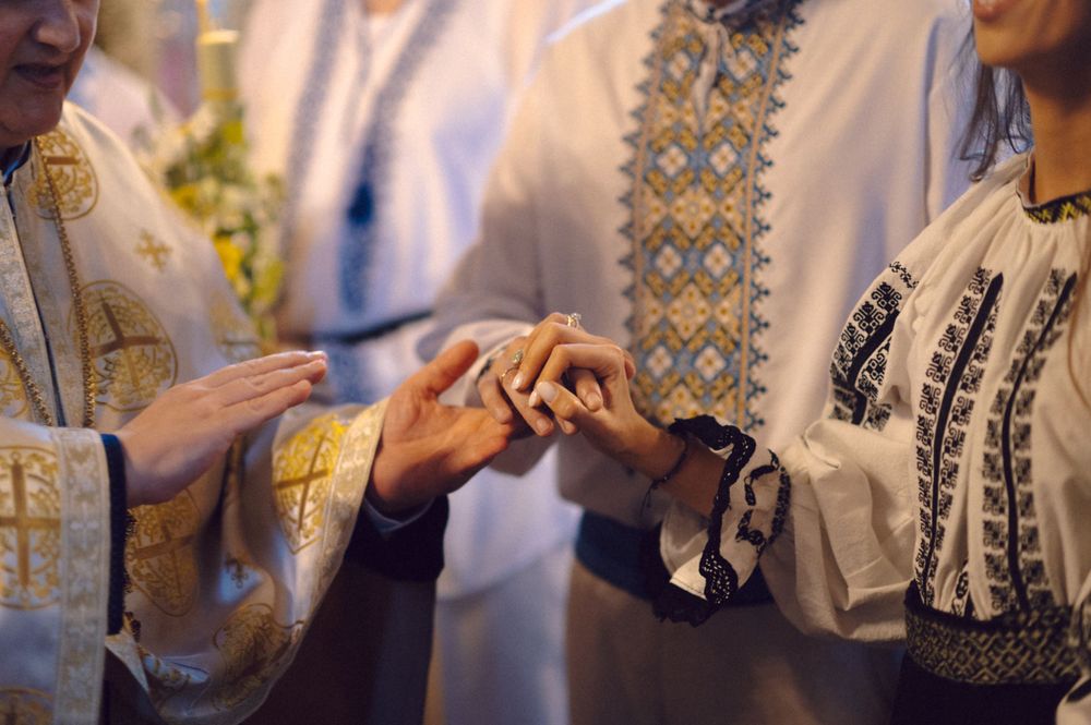 Close-up of hands during Orthodox wedding ring exchange ceremony.
