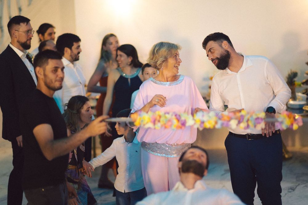 Party guests passing around festive flower garlands during celebration.
