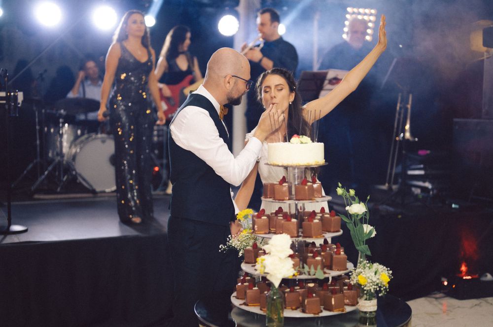 Wedding couple sharing a romantic moment beside their decorated tiered cake.