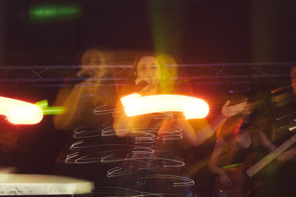 Party guests dancing and posing together on a dimly lit dance floor at celebration event.