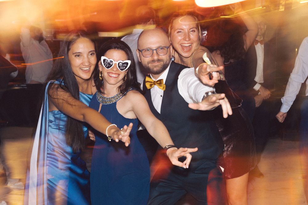 Crowd of party guests dancing together at nighttime celebration with atmospheric lighting.