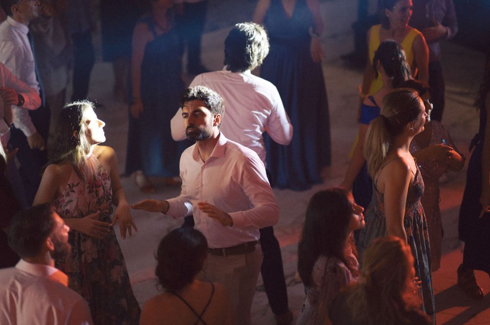 Guest in red dress dances joyfully among crowd at evening celebration event.
