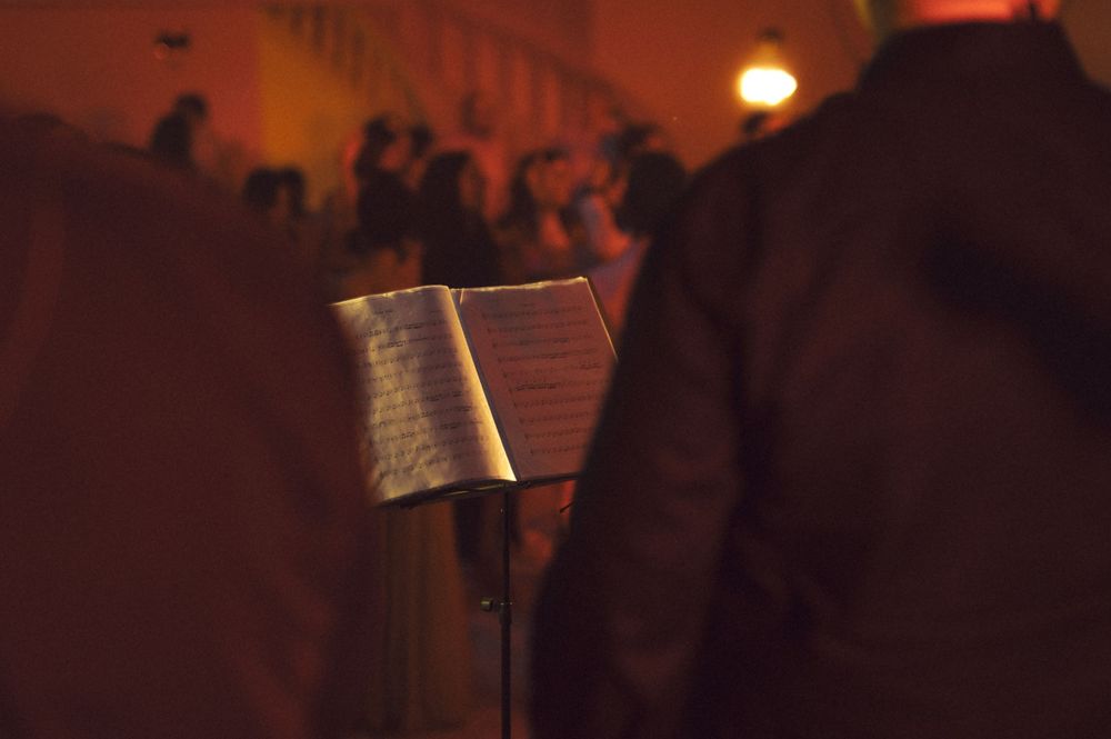 A music stand with sheet music visible in dim red lighting at an event.