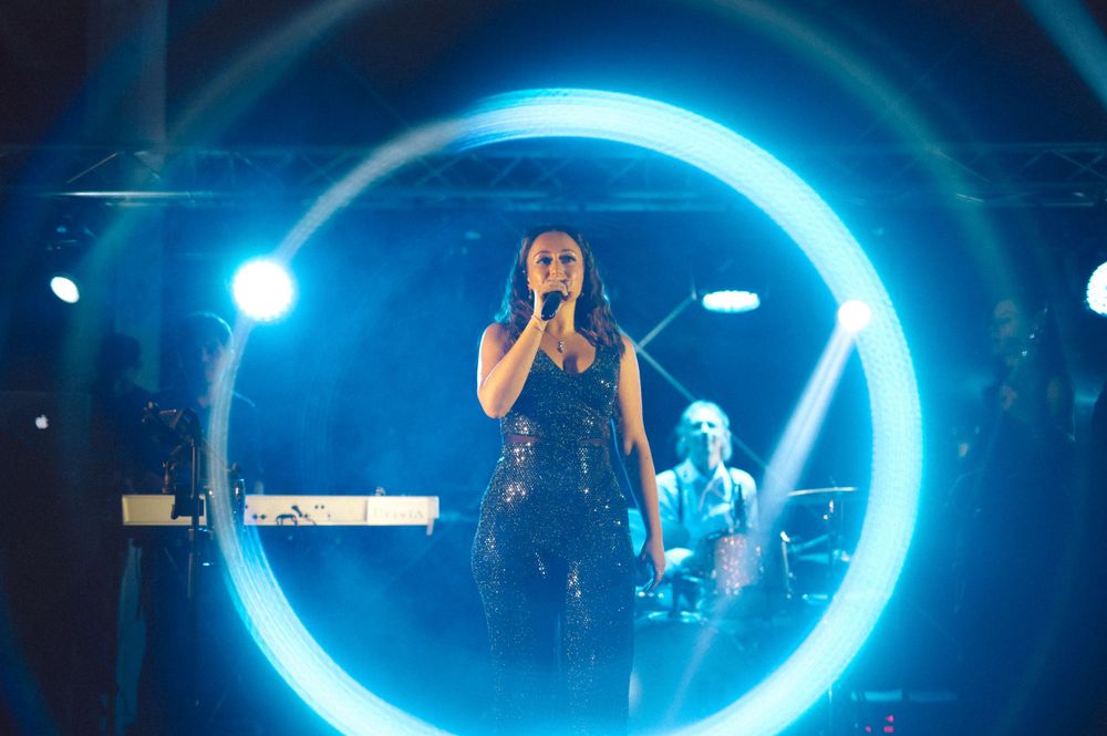 Singer performing on stage with dramatic blue circular lighting effect.