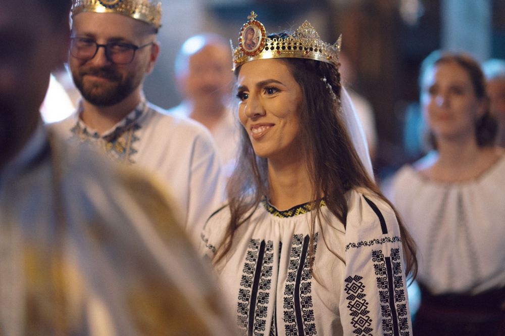 Traditional Orthodox wedding ceremony with crowned bride in embroidered folk dress.
