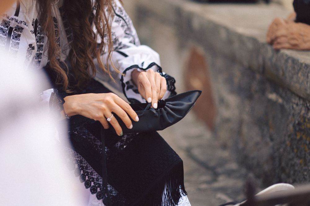 Hands in traditional embroidered clothing hold a dark fabric.