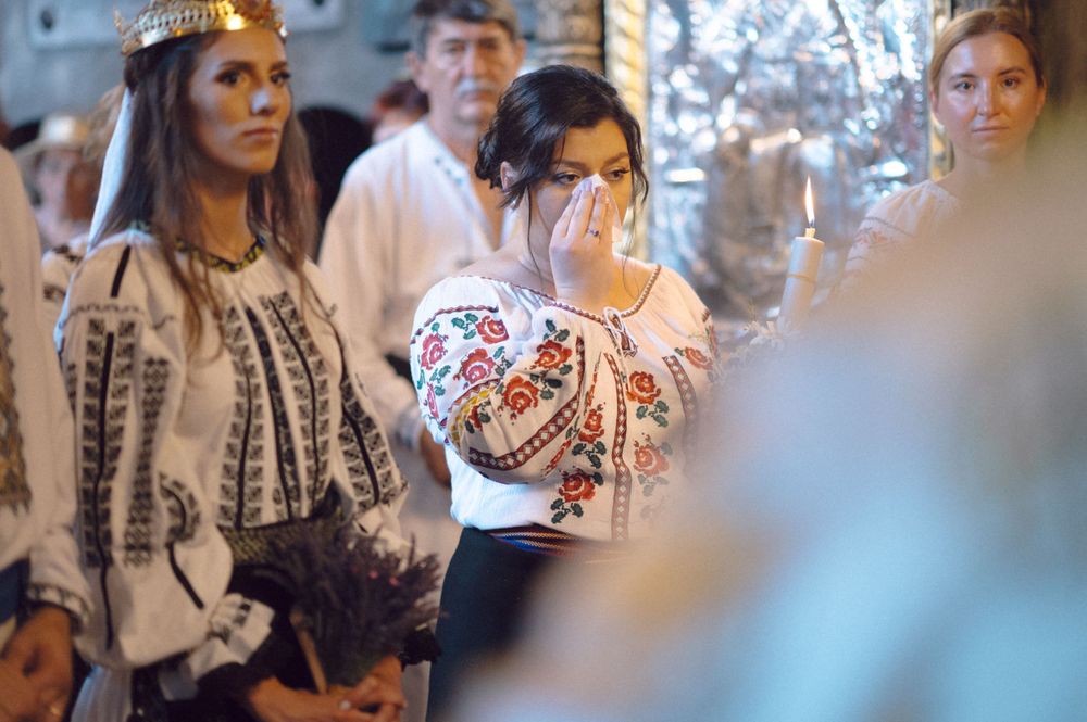 Wedding attendees in traditional embroidered Romanian folk costumes during a ceremony.
