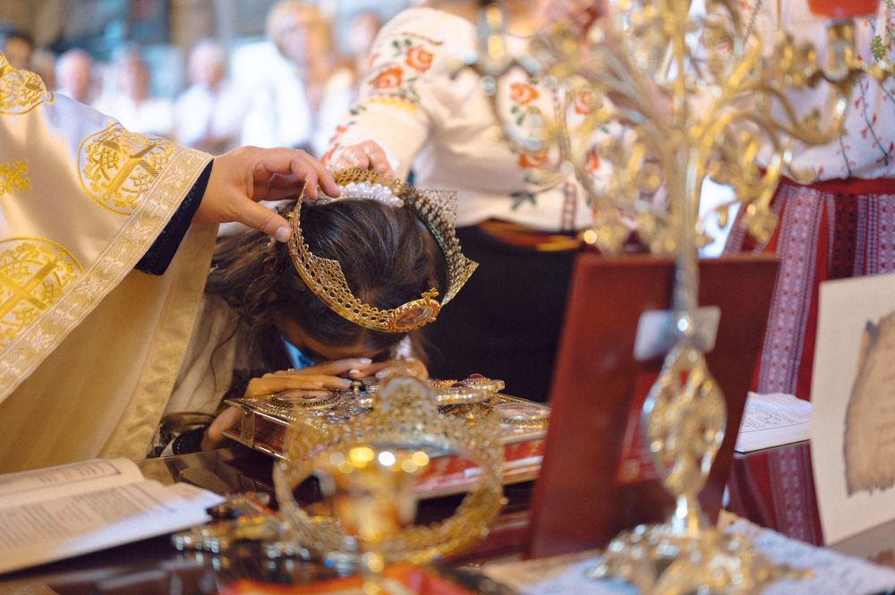 Close-up of ornate golden Orthodox wedding crowns during a ceremonial blessing.