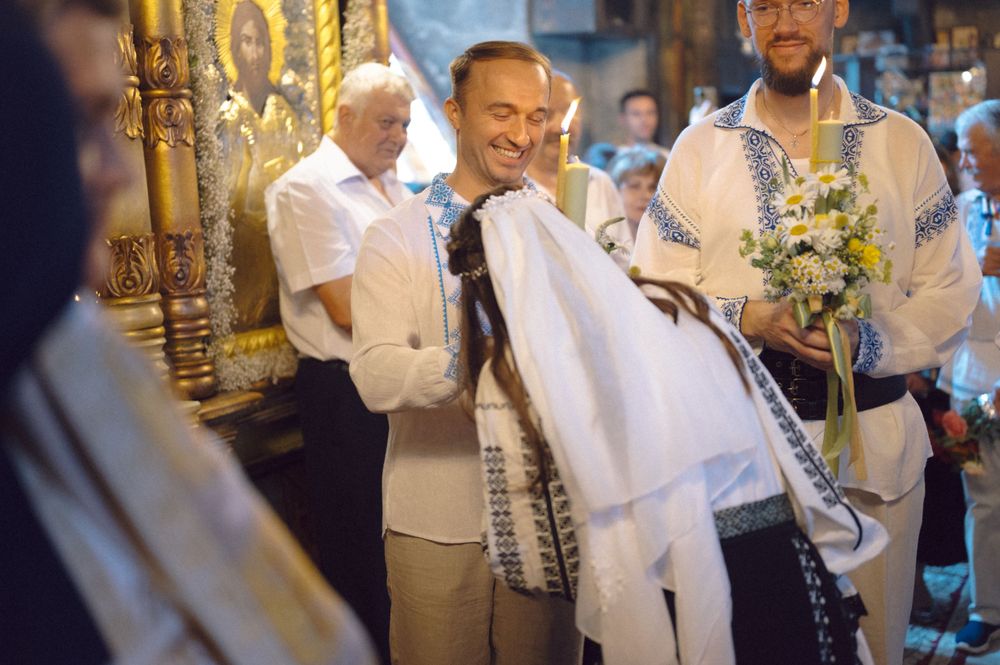 Participants in white attire gather during a traditional Orthodox wedding ceremony.