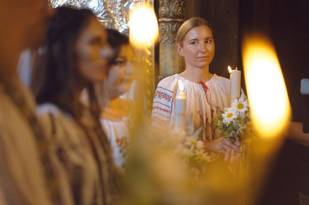 People in traditional folk costumes stand together with candlelight creating a warm ambiance.