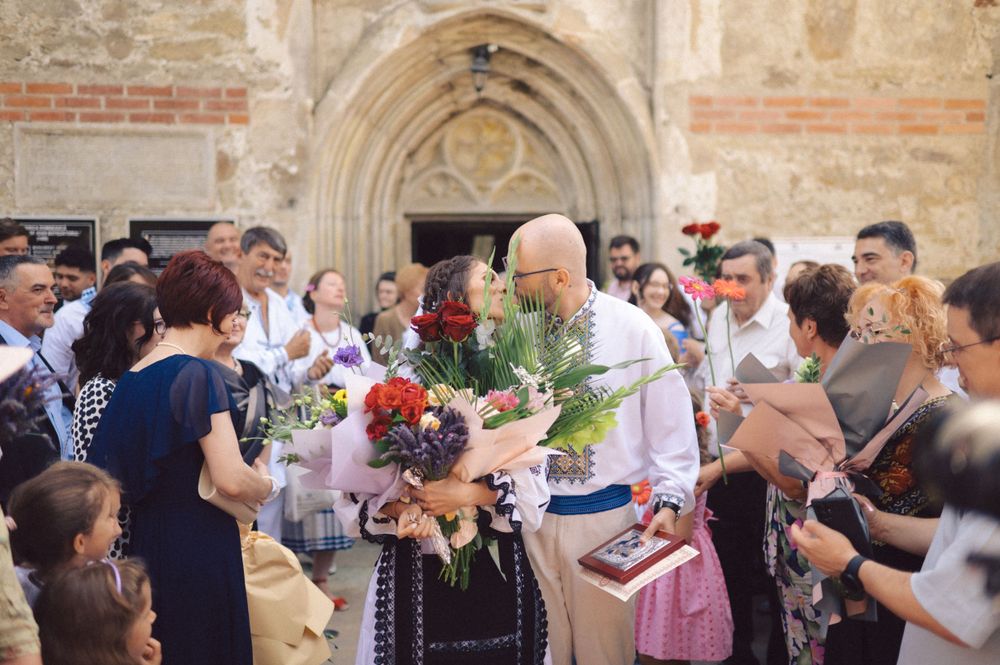 A crowd gathers outside a historic stone church entrance during a celebration.