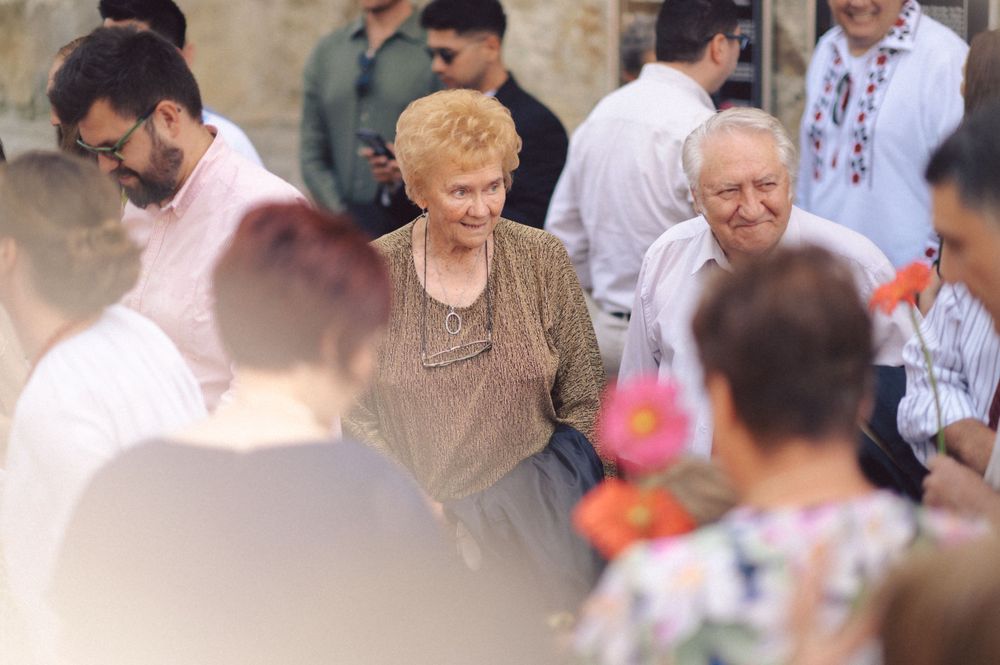 People mingle during an outdoor social gathering near stone architecture.
