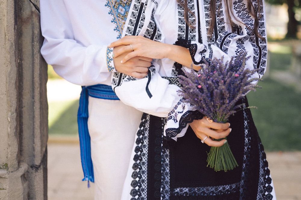 Close-up of traditional Romanian folk costume with embroidery details and lavender bouquet.
