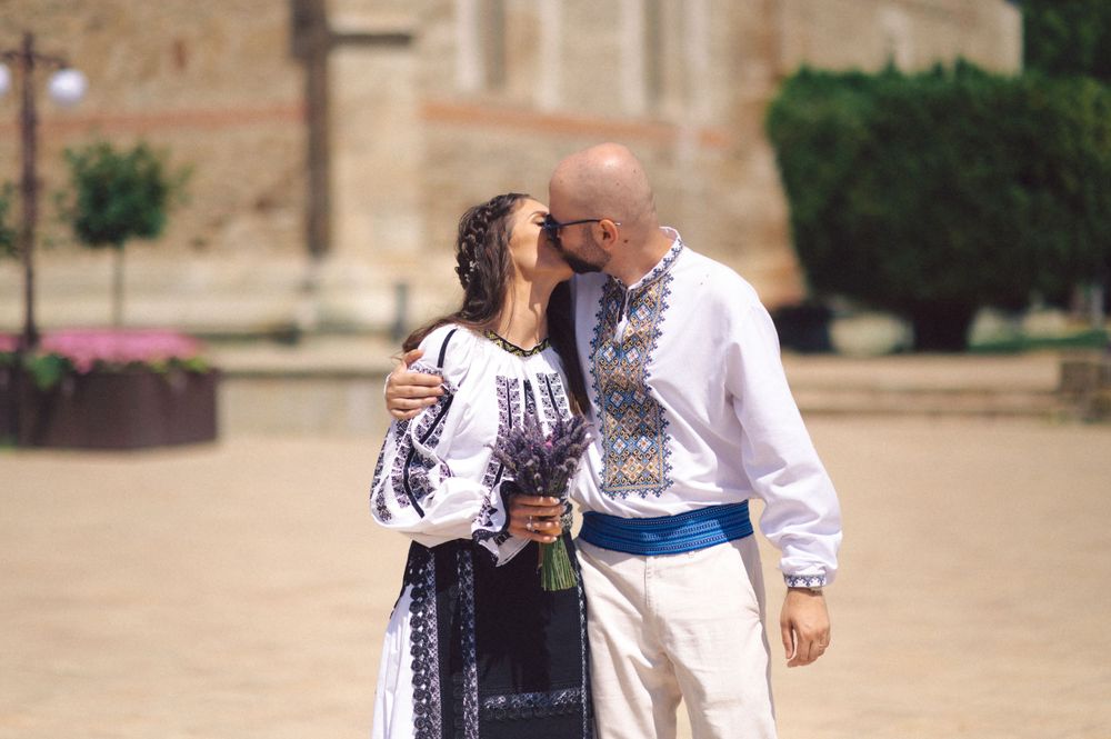 A tender moment captured between a couple in Romanian folk costumes outside a church.