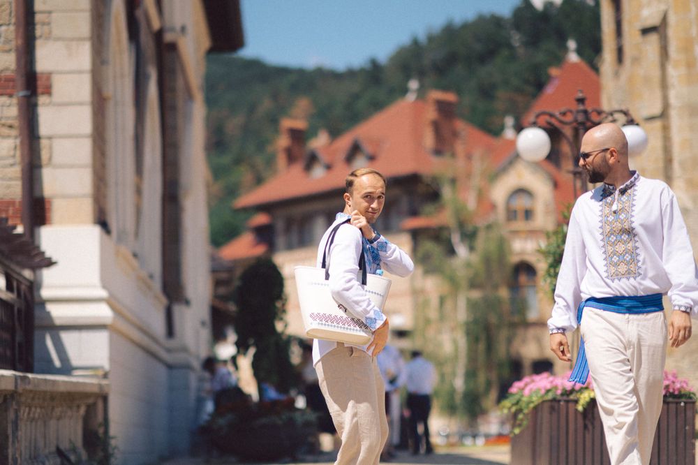 People in traditional white Romanian clothing interacting on a sunny street.