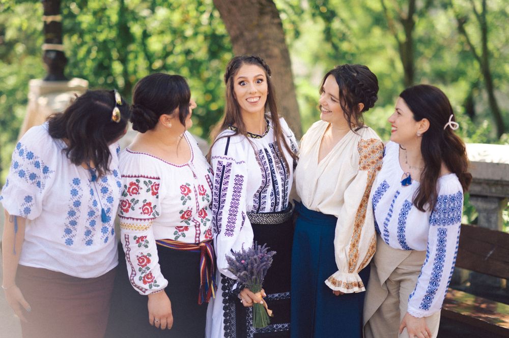 Group of women wearing traditional Romanian blouses with blue embroidery gathering outdoors.