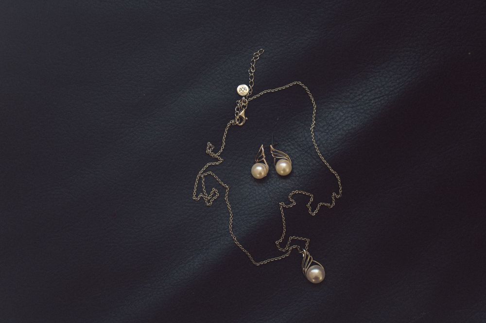 Delicate gold necklace with pearl accents displayed on dark surface.