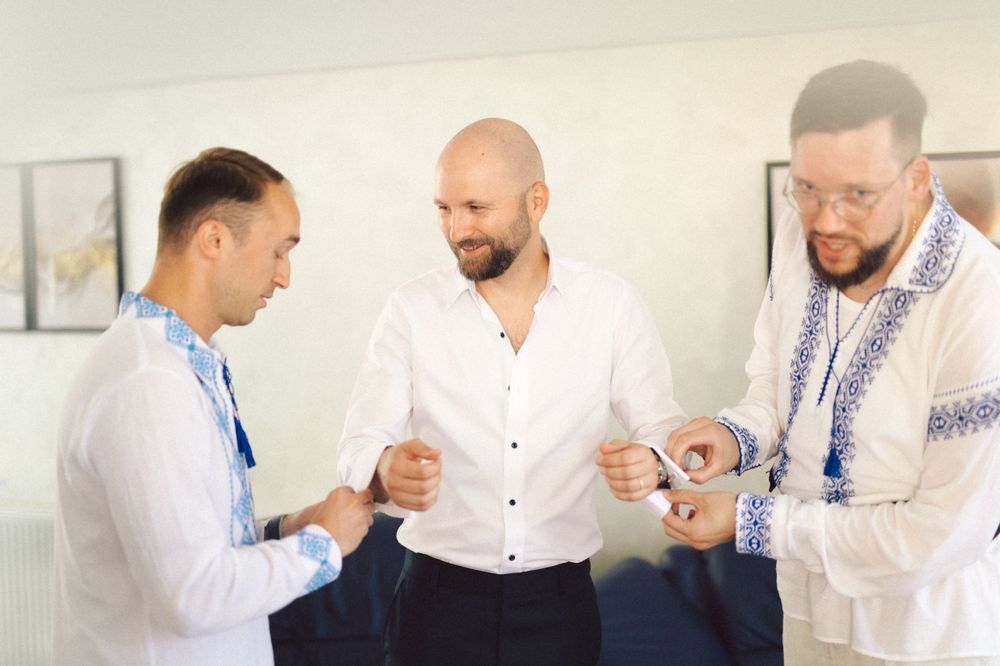 Group getting ready in white shirts with embroidered details preparing for formal event.