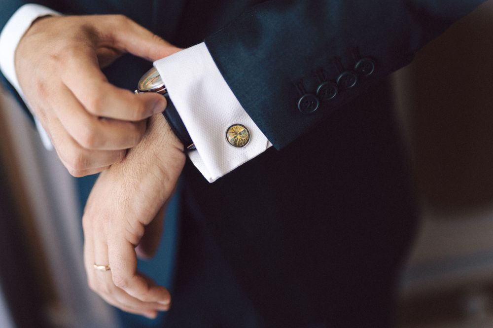 Close-up detail shot of cufflinks and suit sleeve on wedding day.