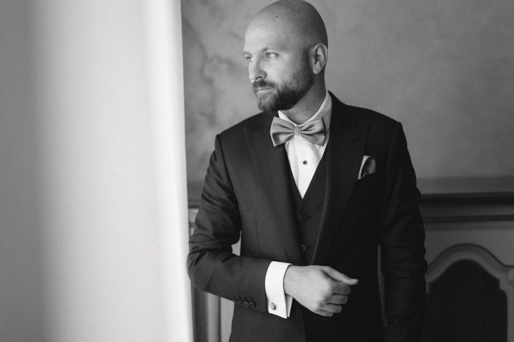 Black and white portrait of groom in formal attire and bow tie.