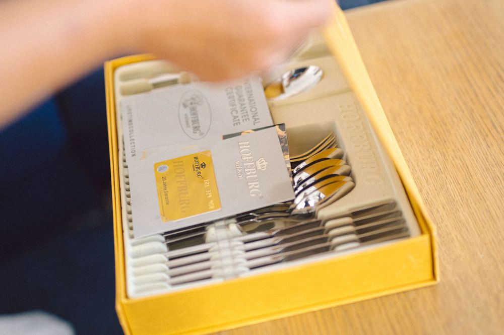 Close-up view of a yellow box containing silverware and utensils being arranged.