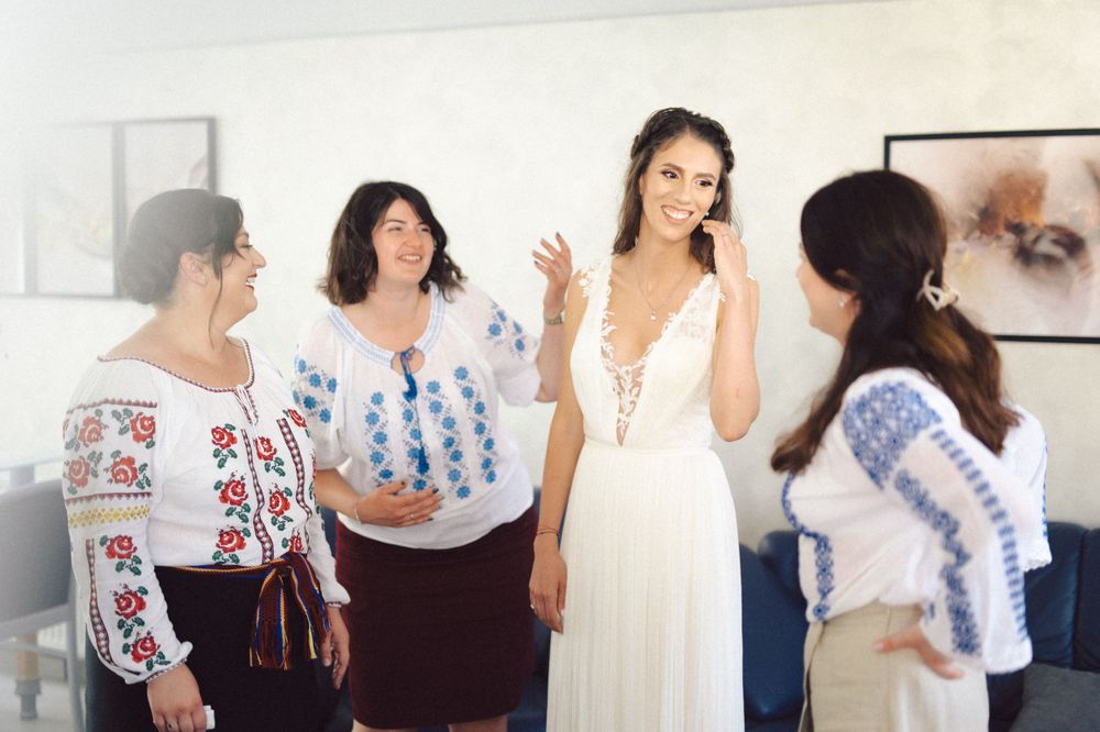A wedding scene with people in traditional embroidered blouses gathered around someone in a white dress.