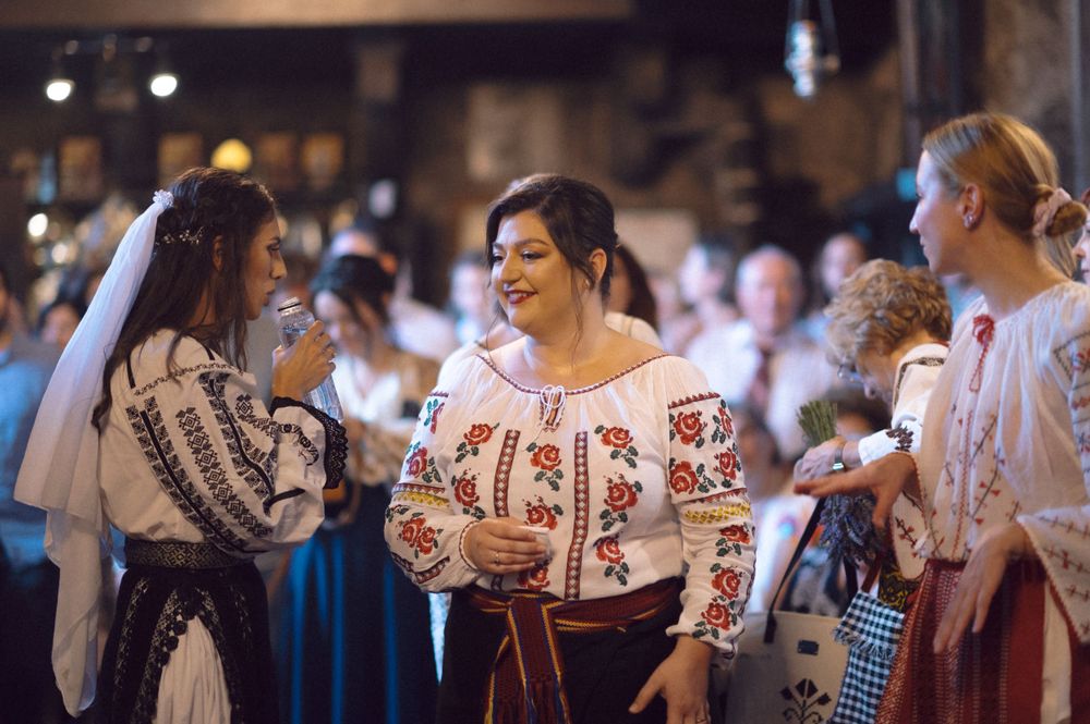 Group wearing traditional Romanian embroidered blouses gather at a celebration.