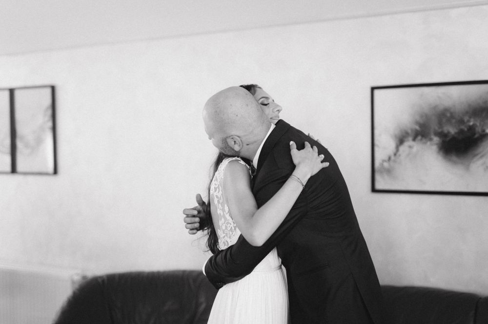Black and white photo of two people embracing during an emotional wedding moment.