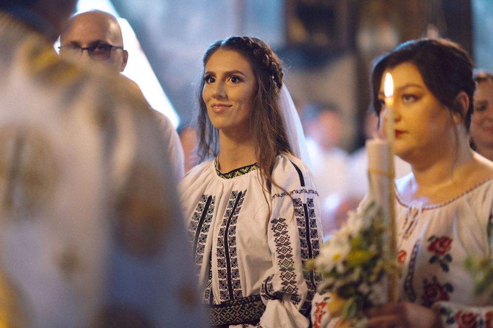 People wearing traditional Romanian folk costumes at a formal event.