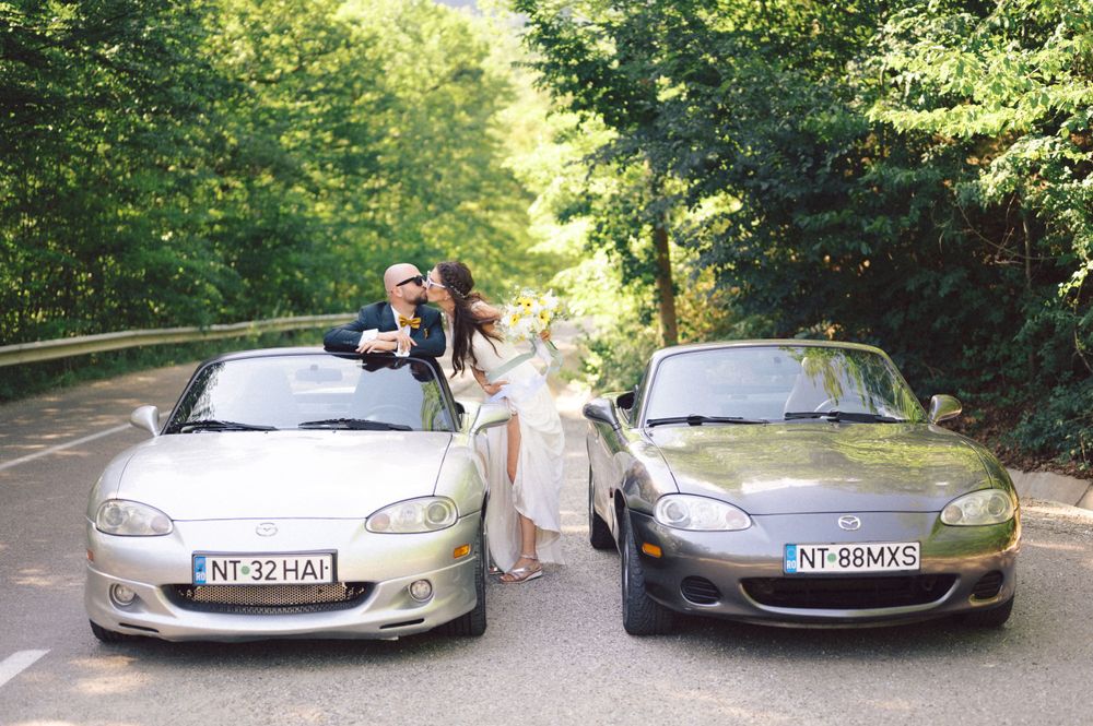 Wedding photography featuring two parked sports cars and celebratory poses.