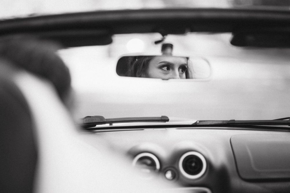 Rearview mirror reflection in a car showing intense eyes focused on the road ahead.