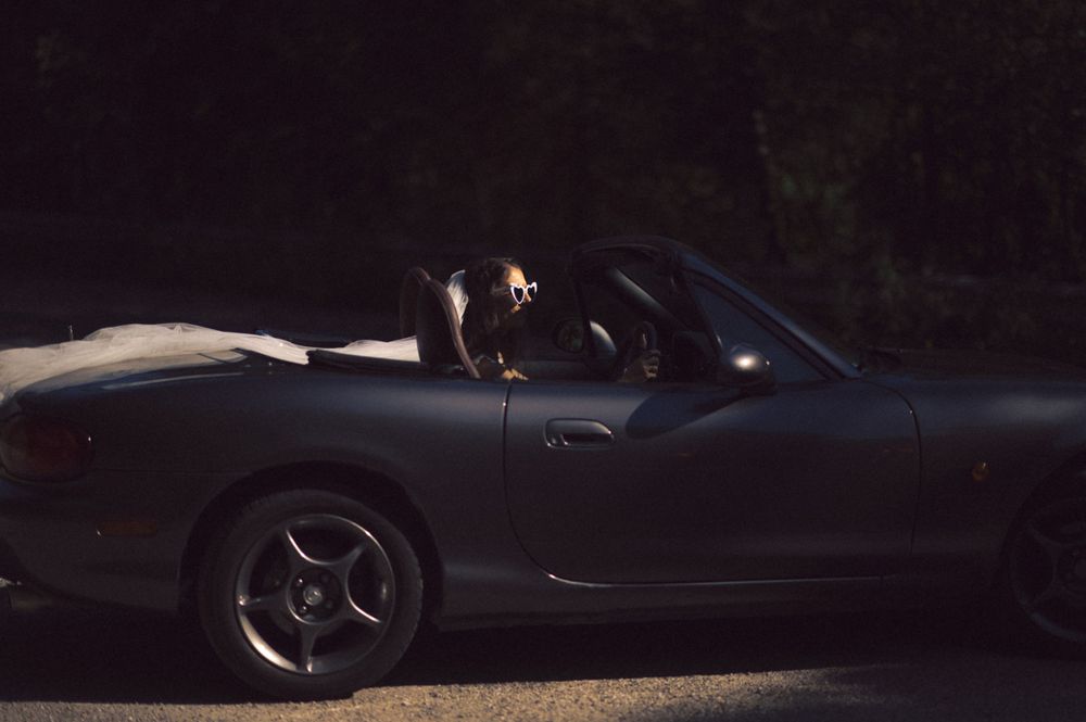 Dark convertible sports car photographed at night with dramatic lighting.