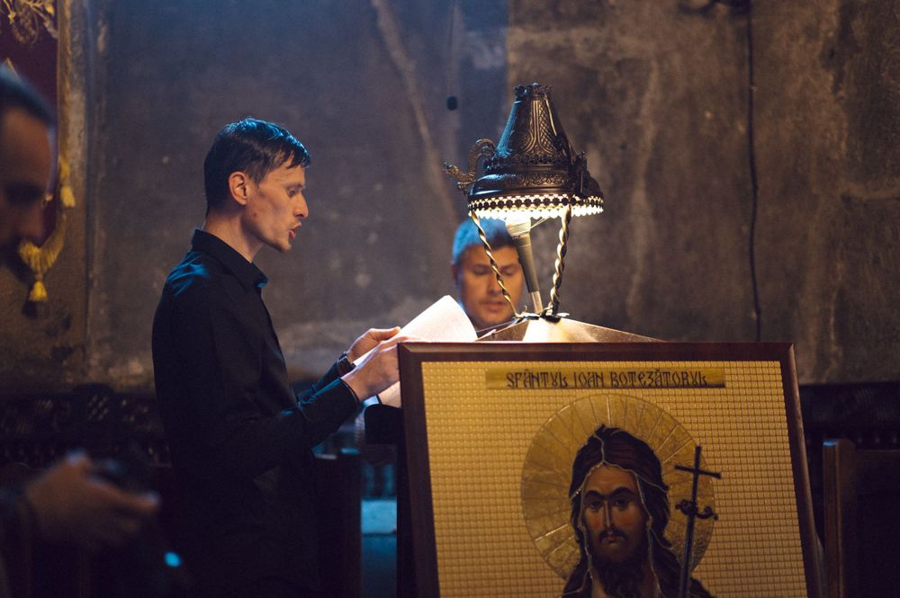 Two people examining a religious icon under lamp light.