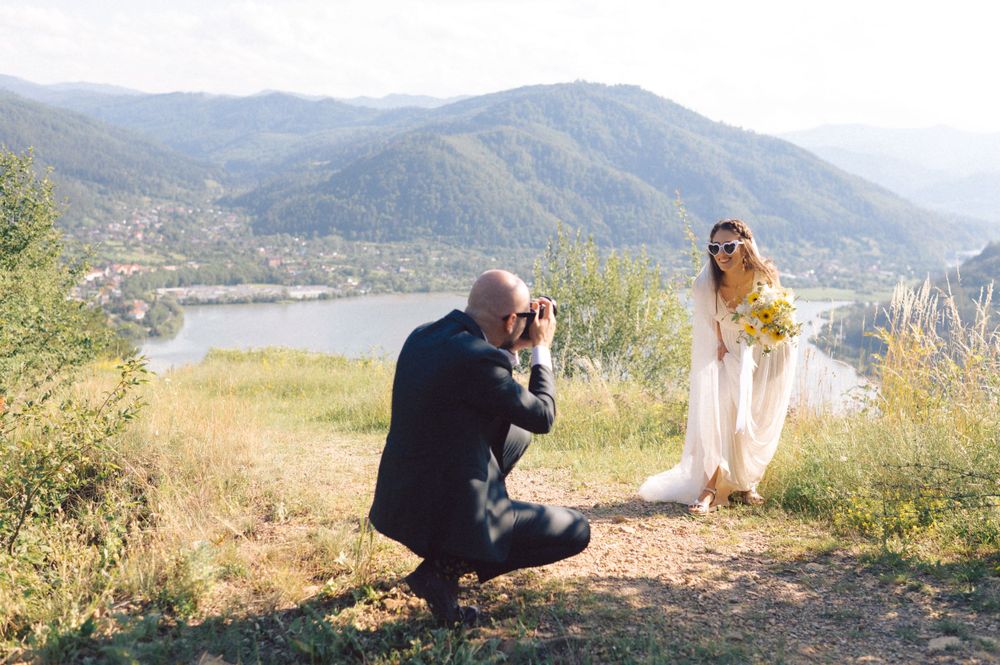 Photographer captures wedding portraits on scenic mountain overlook.